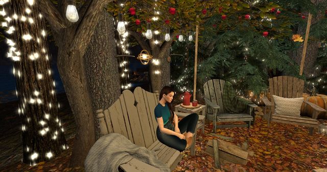 Sitting at a bonfire under apple trees hung with lights, on a weathered bench, coffee on the table.